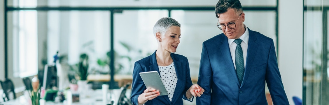 A male and a female in suits talking as they walk